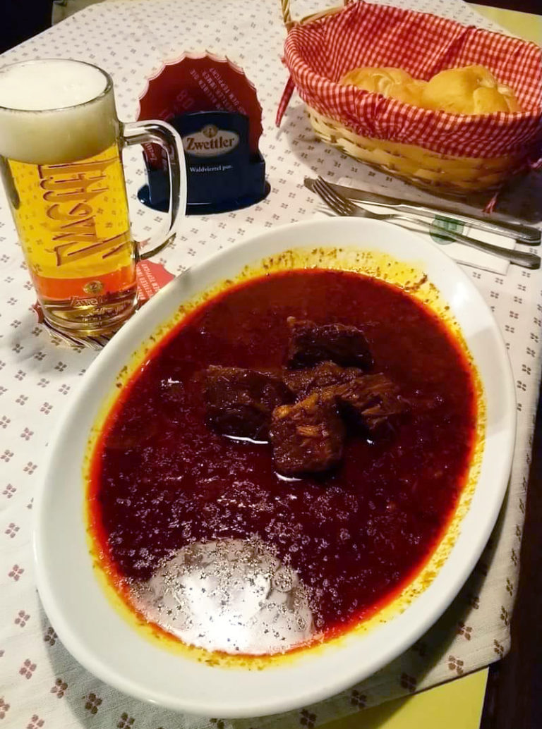 Gulasch mit Glas Bier am Tisch